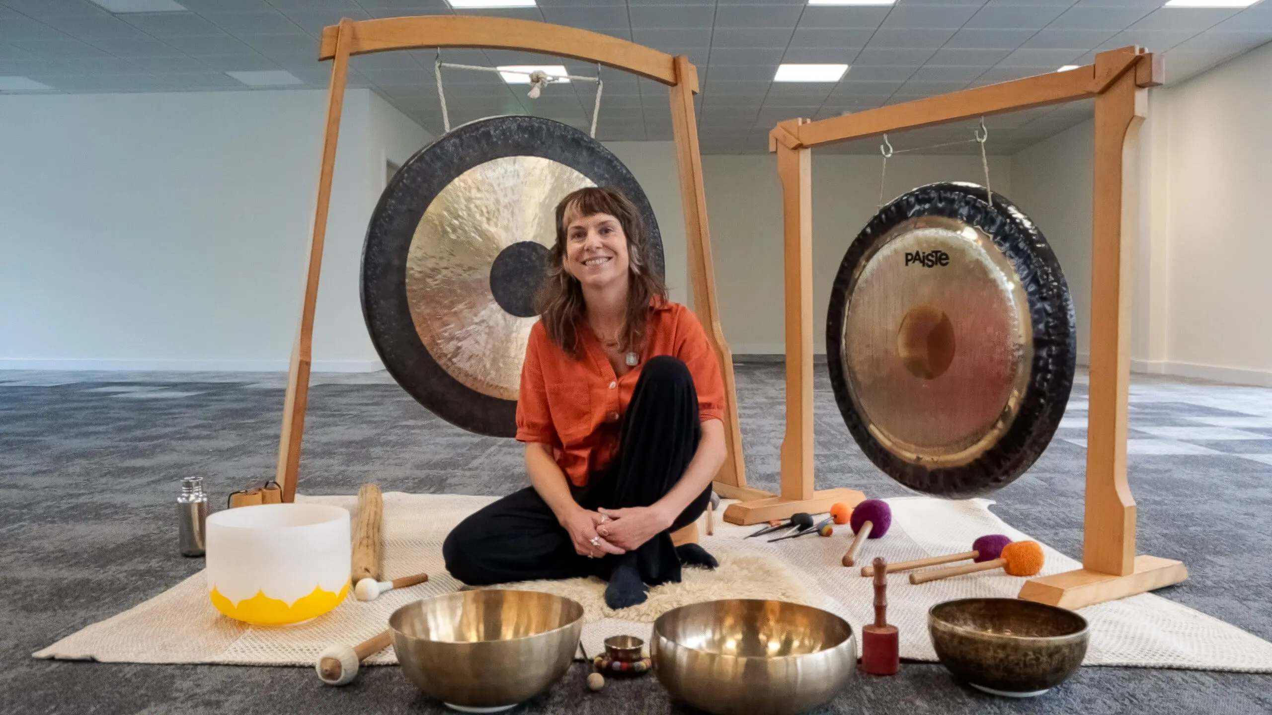Image of Chloe McHugh of Sonas Sounds sitting in front of her singing bowls, gongs, and instruments.