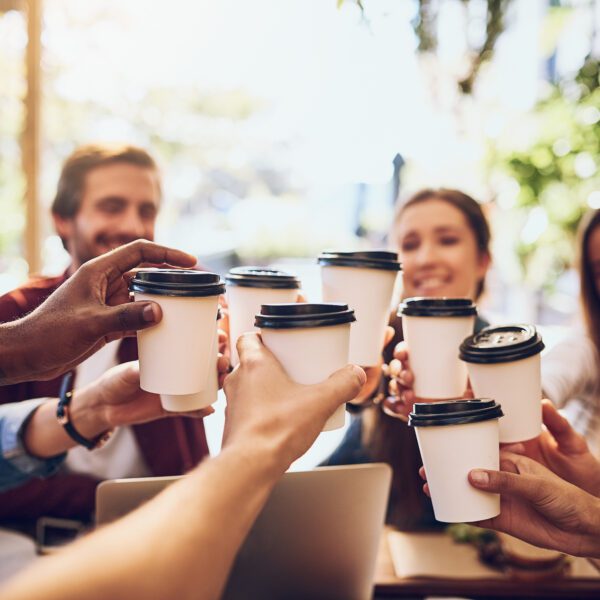 shot of a group of friends toasting with cups of coffee while out together.